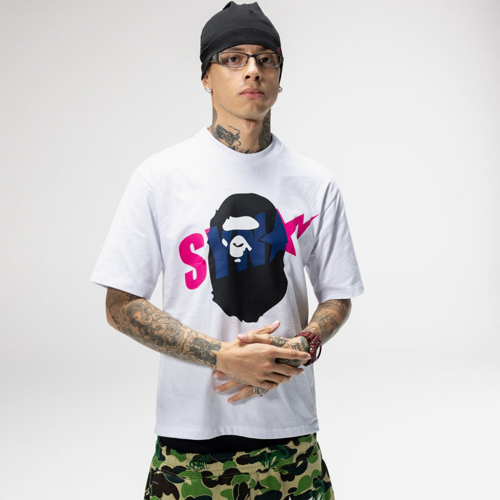 BAPE x Syna World graphic tee featuring a camouflage ape head logo