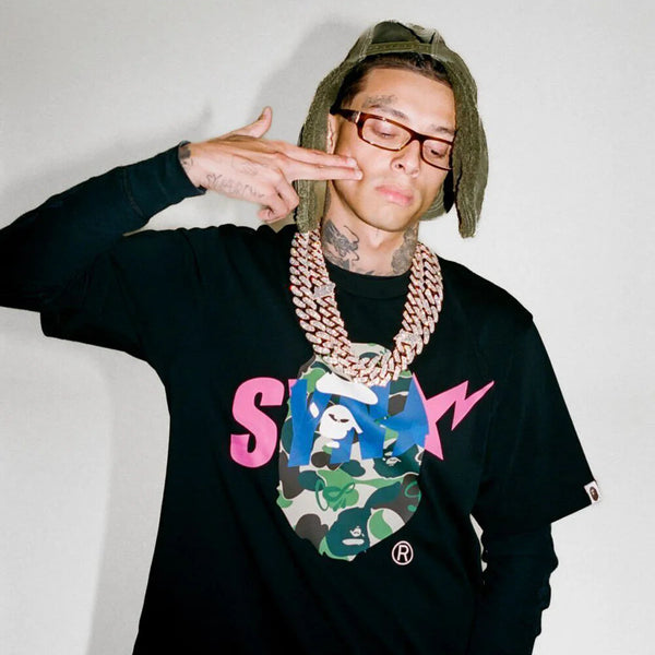 BAPE x Syna World graphic tee featuring a camouflage ape head logo